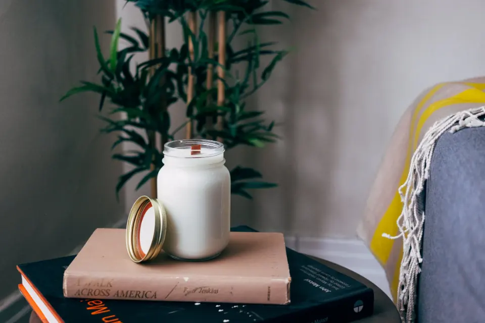 Homemade soy candle glowing in a clear glass jar