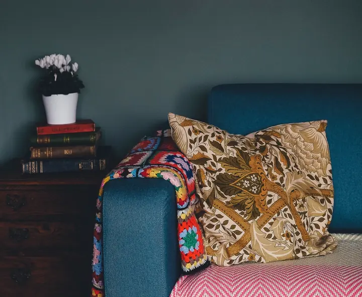 Cozy reading corner with a teal chair and a crocheted blanket