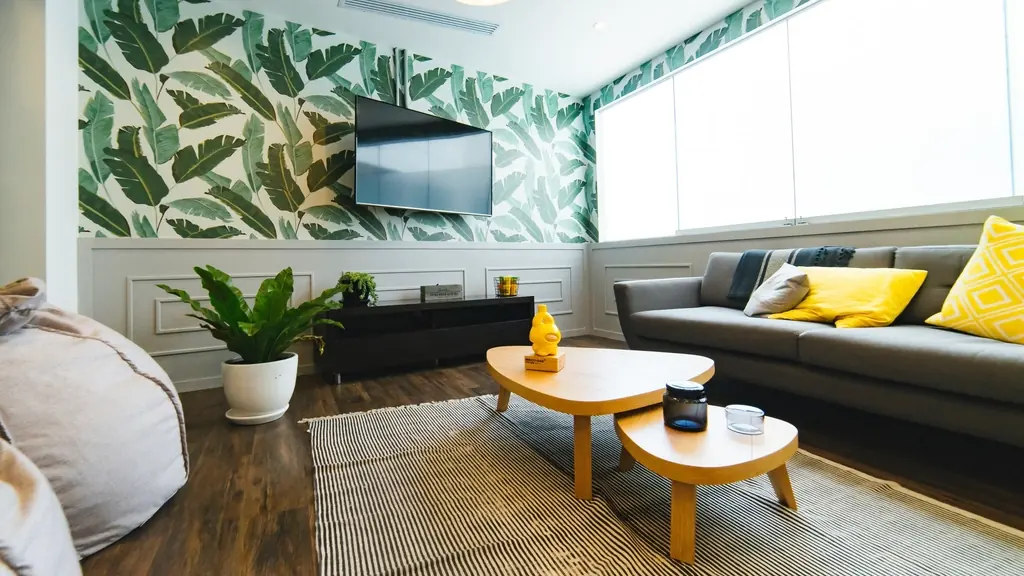 Bright living room with leaf wallpaper, plants and yellow pillows