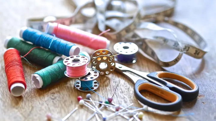 Colorful thread spools, scissors and pins from a sewing kit